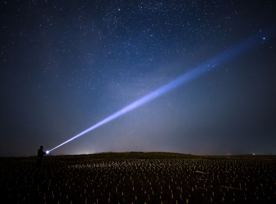 察尔森水库旁的田埂，一道车灯从左下斜着打向夜空，天上稀疏地亮着几颗星