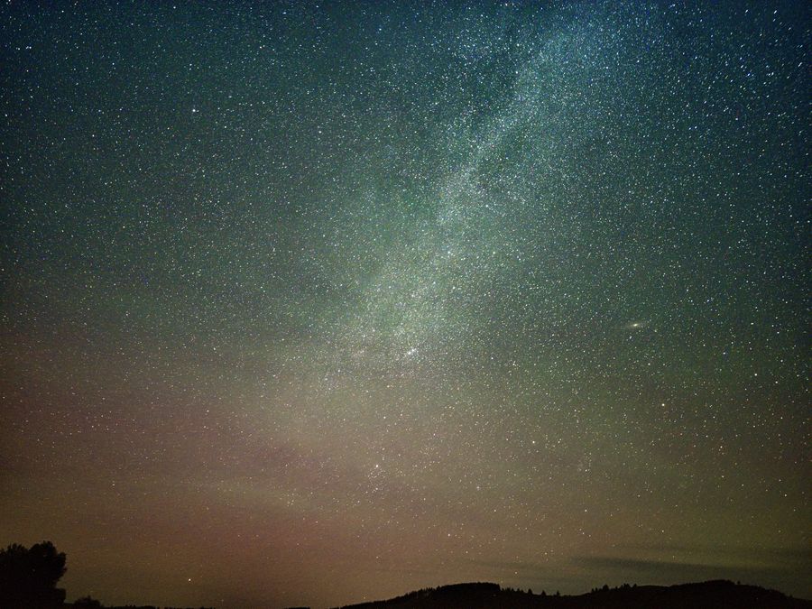 下地窖子的山脊上方，银河斜贯夜空，远处地平线有一小片暖色的光