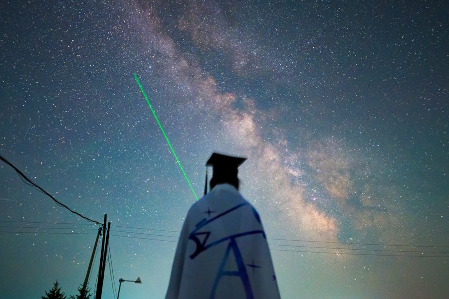毕业生举着绿色激光笔，光柱笔直射向银河，人在画面中央成剪影