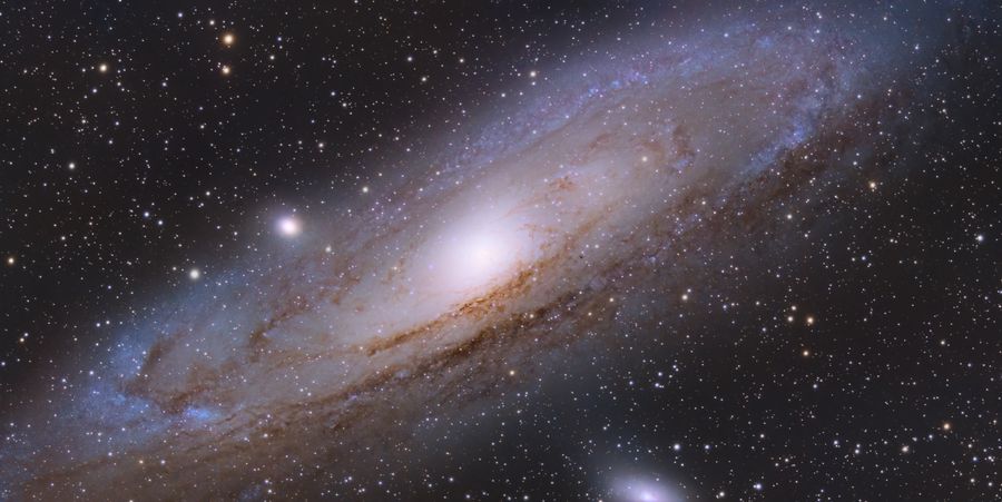 仙女座星系的宽幅画面，明亮的核球与两侧的尘埃带清晰可辨